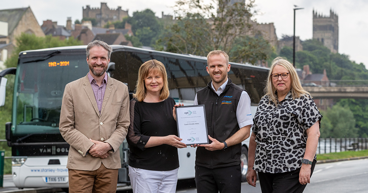 four people stood in front of a coach holding award at Durham City Centre